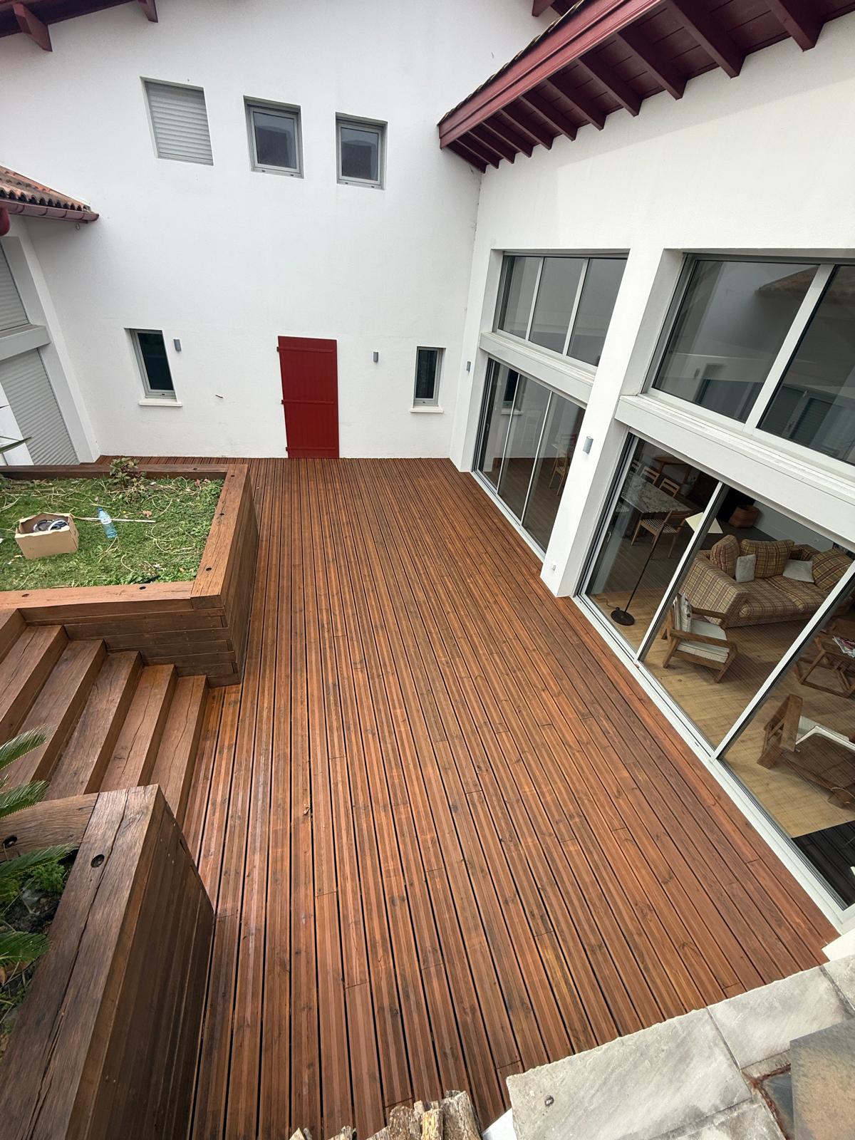 Terrasse bois protégée devant une maison basque traditionnelle